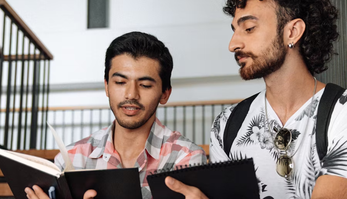 Two male students conferring over books